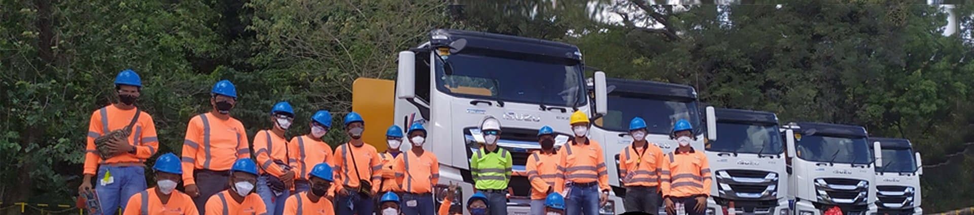 Trainees in safety gear lined up in front of trucks